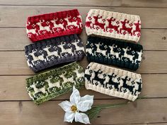 four knitted headbands sitting on top of a wooden table next to a white flower