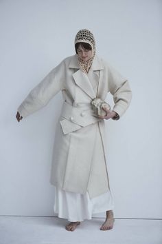 This sweeping statement coat exudes oversized elegance with its wide lapels leading to a romantic deep V neckline. Falling just above the ankles, the Snegurochka Cream Wool Hemp Shell Buttons Coat is both cozy and sophisticated. Made from a blend of durable hemp and wool fibers, its sturdy structure is punctuated with uniquely handcrafted ceramic shell buttons. Lined.Composition 40% Hemp 60% Wool and it´s undyed.Lining 100% viscoseTrimming 100% ceramic glazed handmade shell buttonsSizesOversize. Oversized Beige Pea Coat With Lapel Collar, Chic Notch Lapel Pea Coat For Spring, Beige Oversized Wool Coat With Lapel Collar, Oversized Beige Shawl Collar Outerwear, Beige Shawl Collar Outerwear For Spring, Chic Long Wool Coat For Spring, Single Breasted Shawl Collar Outerwear For Spring, Elegant Oversized Beige Wool Coat, Spring Single Breasted Shawl Collar Outerwear