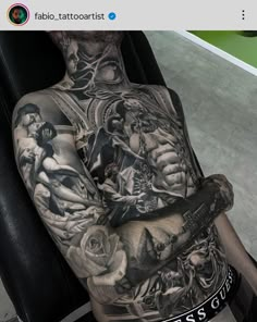 a man with tattoos on his back sitting in a chair