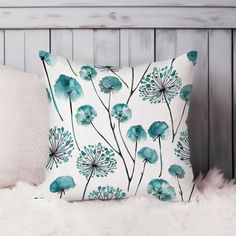 a pillow with blue flowers on it sitting on a white furnishing next to a wooden headboard