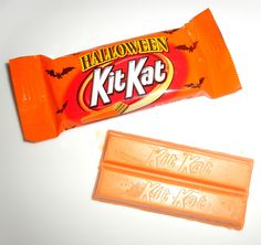 an orange halloween kitkat candy bar next to it's wrapper on a white surface