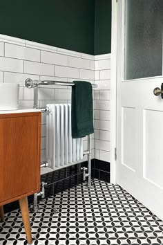 a bathroom with black and white tile flooring and green accents on the walls, along with a radiator