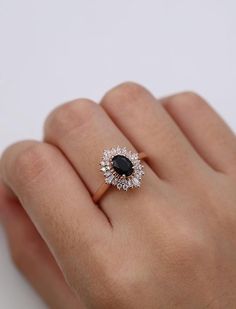 a woman's hand with a diamond and black stone ring