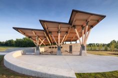 an outdoor covered area with benches and grills on the outside wall, surrounded by green grass