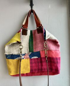 a multicolored purse hanging from a hook on a wall with a leather handle