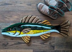 a stuffed fish laying on top of a wooden floor next to a pair of shoes