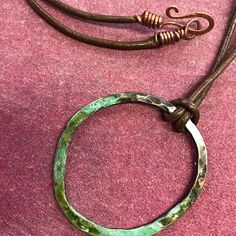 a necklace with a metal ring and green pattered paint on the inside of it