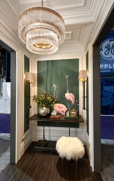 a room that has a table with some flowers on it and a lamp hanging from the ceiling