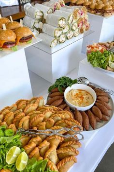 many different types of food are displayed on the buffet table, including sandwiches and other appetizers