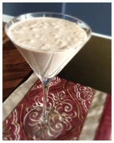 a martini glass filled with white liquid on top of a red and white table cloth