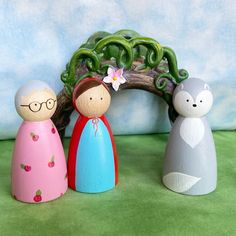 three wooden dolls are standing in front of a small arch with a flower on it