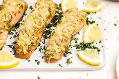 two fish fillets on a plate with lemons and parsley