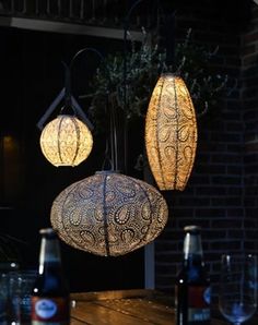 three lights hanging from the ceiling above a table with wine glasses and bottles on it