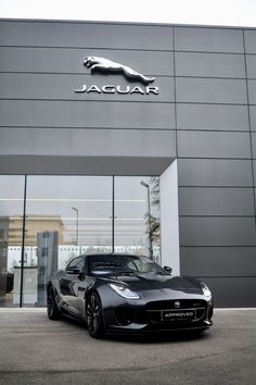 a black sports car parked in front of a jaguar dealership with the logo on it