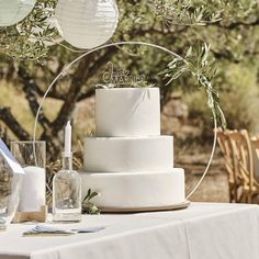 a white wedding cake sitting on top of a table next to wine glasses and candles