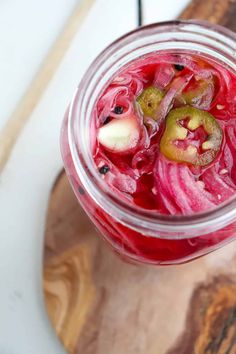 a jar filled with red liquid sitting on top of a wooden cutting board