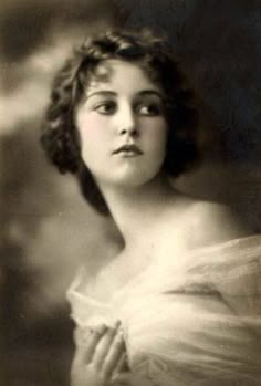 an old black and white photo of a woman in a dress looking off to the side