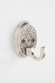 an elephant shaped hook is mounted on the side of a white wall with a decorative design