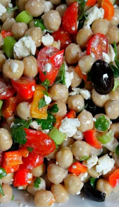 a salad with chickpeas, carrots, tomatoes and feta cheese on it