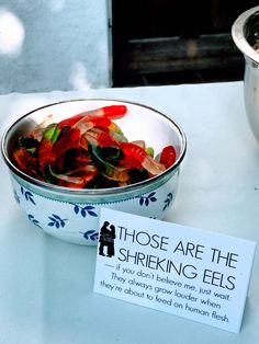 there is a bowl with gummy bears in it and a sign on the table