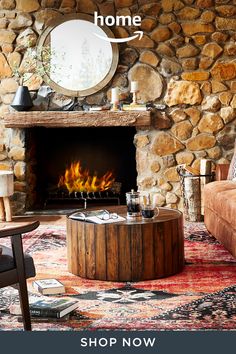 a living room filled with furniture and a fire place in front of a stone wall