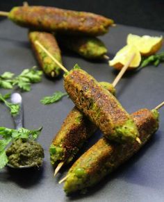 several skewers of food on a table with herbs and other things to eat