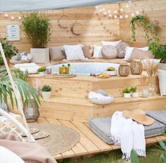 an outdoor hot tub surrounded by potted plants and greenery in a wooden deck