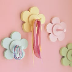 paper flowers and ribbons hang on the wall next to each other in various shapes, sizes and colors