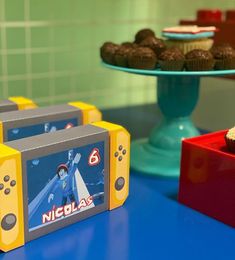 two nintendo wii game controllers sitting on top of a blue table next to cupcakes