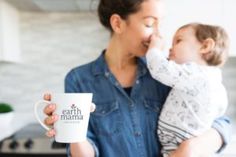 a woman holding a baby and drinking out of a cup