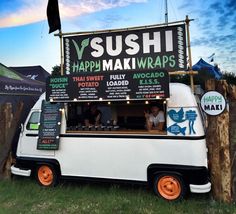 a food truck parked in the grass with sushi and happy maki wraps on it's side