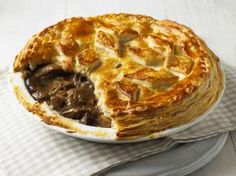 a beef pot pie on a plate with a piece cut out