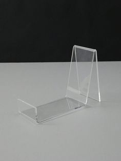 a clear acrylic display stand on a white table with black background and no one around it