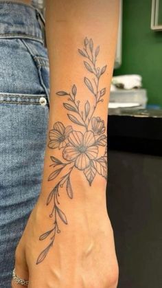 a woman's foot with a flower tattoo on her left wrist and the bottom part of her arm