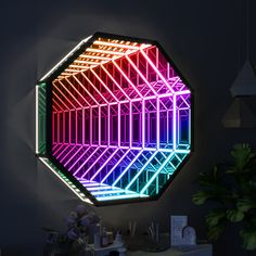 a colorful light up mirror sitting on top of a table next to a potted plant