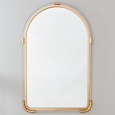 an arched mirror on the wall with a gold frame and metal trim around it's edge