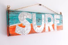 a wooden sign with the word surf hanging on a wall in front of a white wall