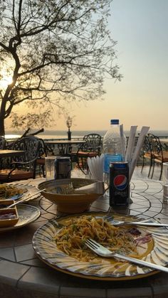 a table topped with plates of food next to a bottle of water and glasses on top of it