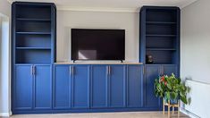 a living room with blue bookcases and a flat screen tv on the wall