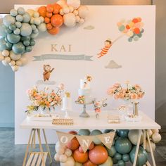 a table topped with balloons and cake next to a wall