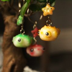 three little fish keychains hanging from a tree branch in front of a plant