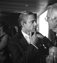 black and white photograph of two men in suits talking to each other at an event