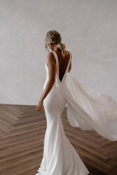 a woman in a white dress is standing on a wooden floor with her back to the camera