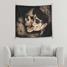 a white couch sitting next to a wall with a clock and two skulls on it