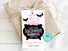 a gift bag with a tag that says happy halloween and bats on it, sitting next to a brown package