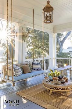 A cozy porch bathed in sunlight, featuring a hanging swing with plush cushions, a wicker table with decor items, and serene natural surroundings, creating a peaceful outdoor retreat. Bobby Berk, White Accent Pillow, Vibrant Home, Southern Living Homes, Bed Swing, Modern Beach House, Design Apartment, Modern Beach, Home Inspo