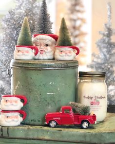 three santa clause figurines sitting on top of a green tin can next to a christmas tree