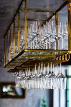 a bunch of wine glasses hanging from a rack in a room with other items on it