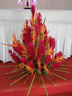 red and yellow flowers in front of a white table cloth on a red carpeted floor