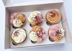 six cupcakes in a white box with pink, orange and white frosting